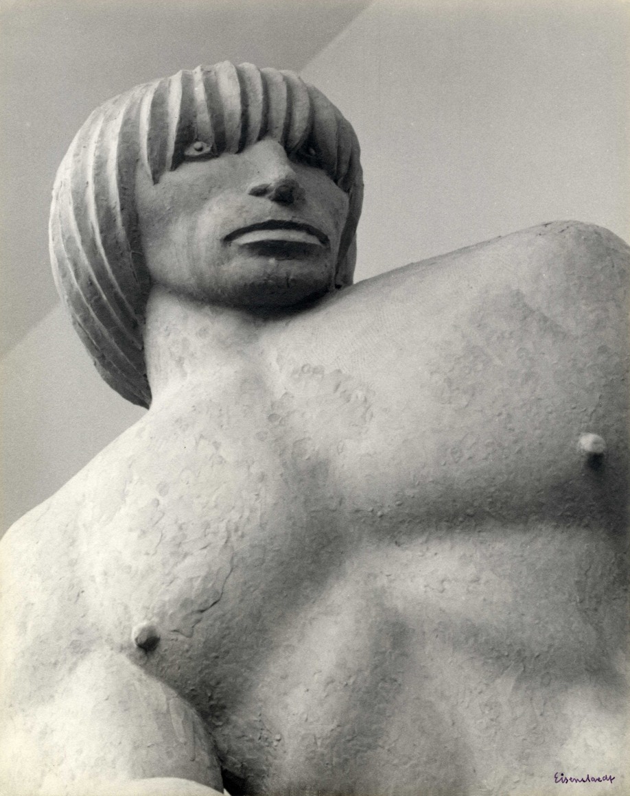 Black and white photo of an imposing figure, sculpted in clay, photographed from a dramatic angle.
