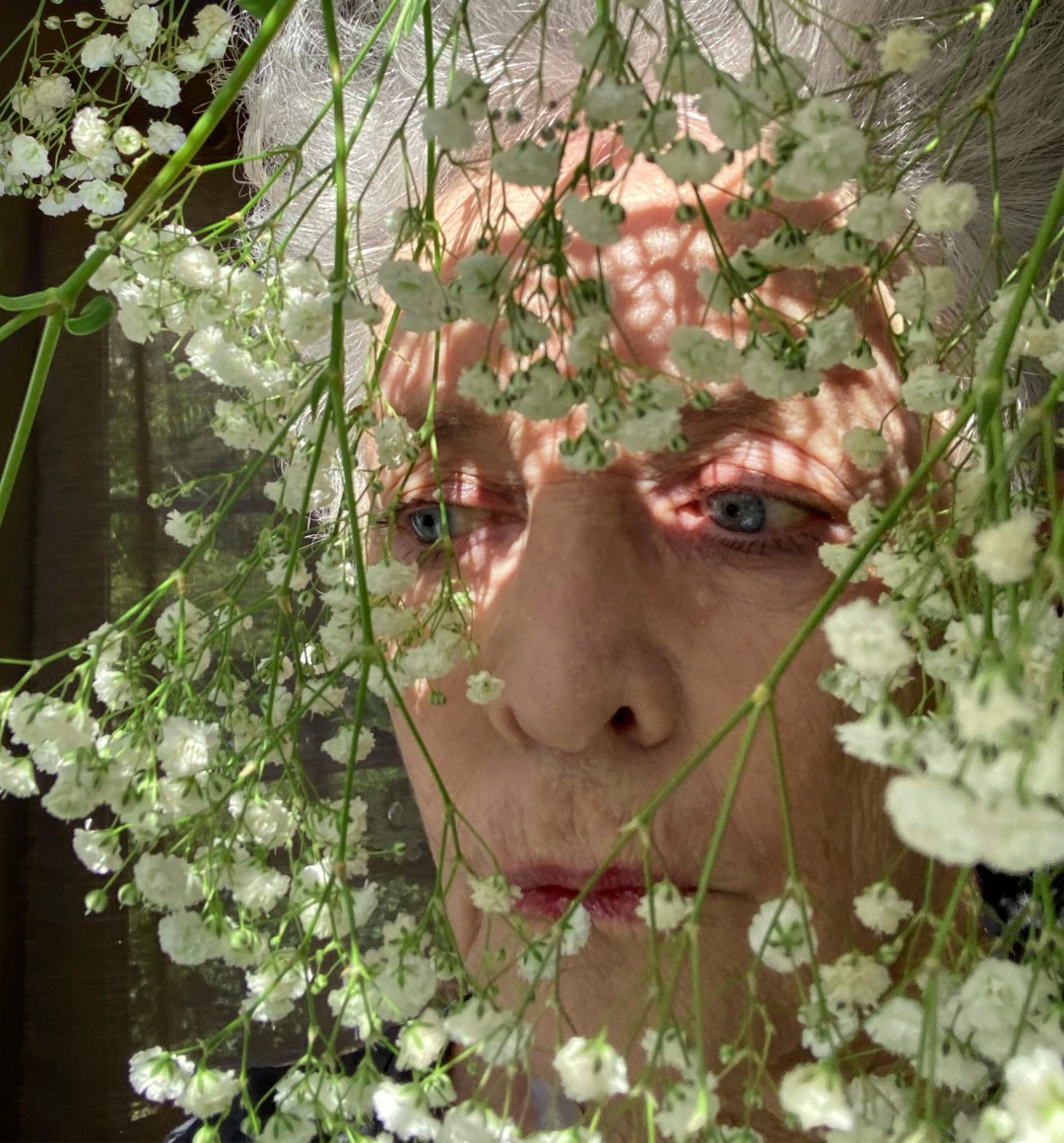 Close up self portrait of the artist&mdash;older white haired woman&mdash;looking through a Baby's Breath pant.