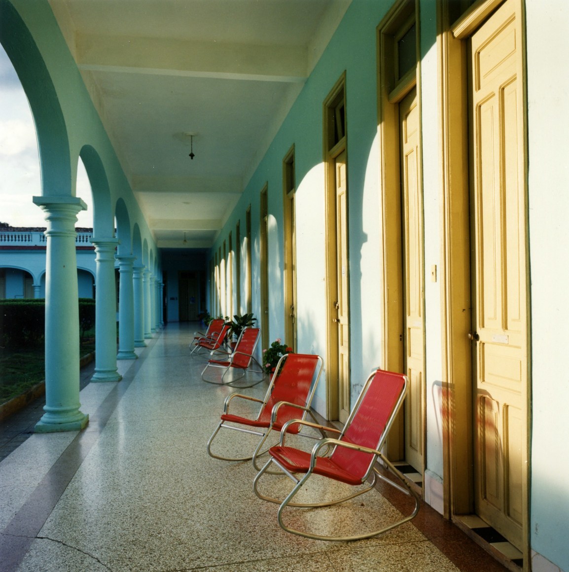 Color photo of a row of colorful chairs lined up on a long outdoor terrace.