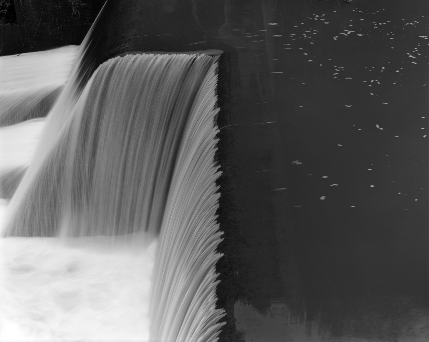 Black and white long exposure photo of water flowing over a dam.