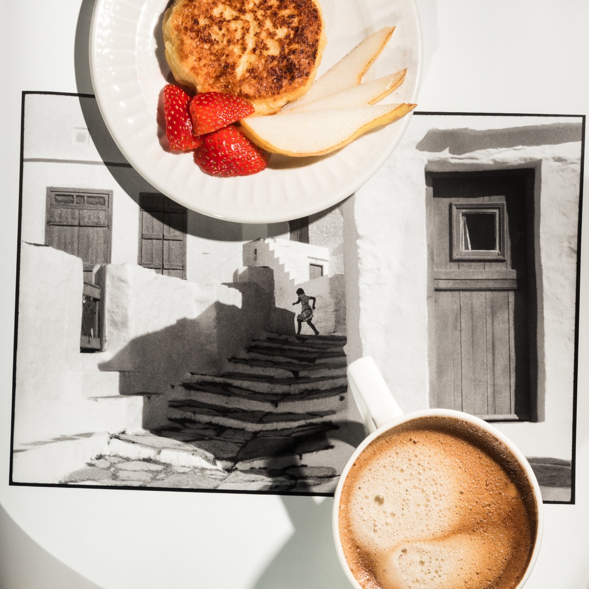 Black and white photograph of Henri Cartier-Bresson photograph of a child running up the stair with coffee ond a plate of breakfast foods on top.