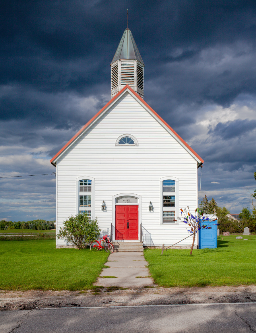 Color photoo of a midwestern church under stormy skies.
