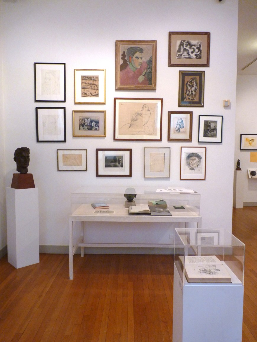 Cropped image showing only the left wall in the previous description. An open book in a glass box on a rectangular mount in now more prominent on the right front of us.