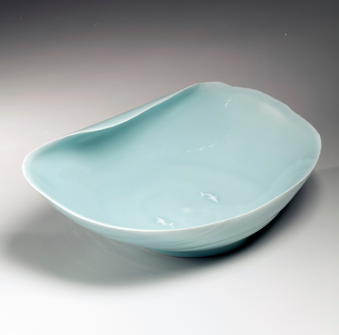 Rounded shallow bowl with furling rim and two carp in relief in interior, ca. 1995