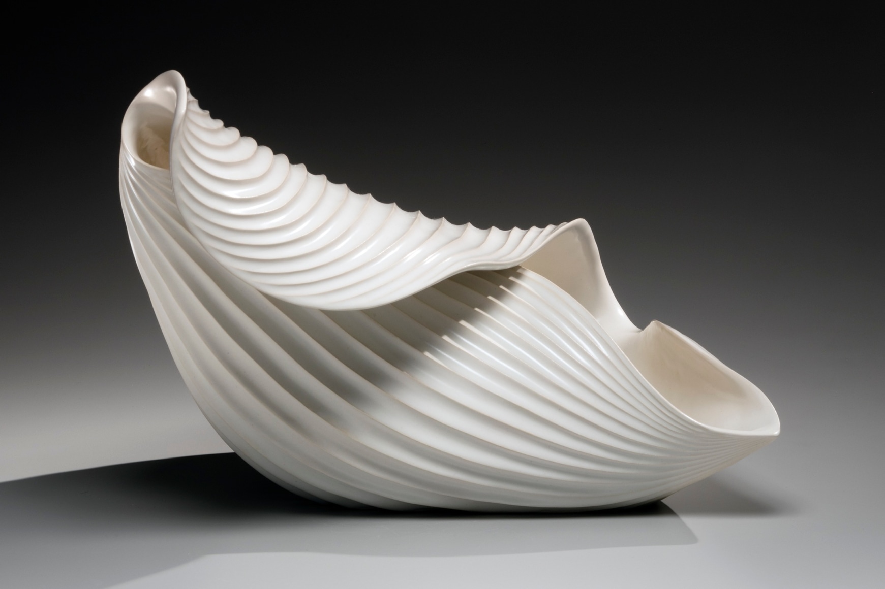 Horizontal ribbed, curled leaf-shaped sculptural vessel with undulating open mouth and creamy white-matte glaze