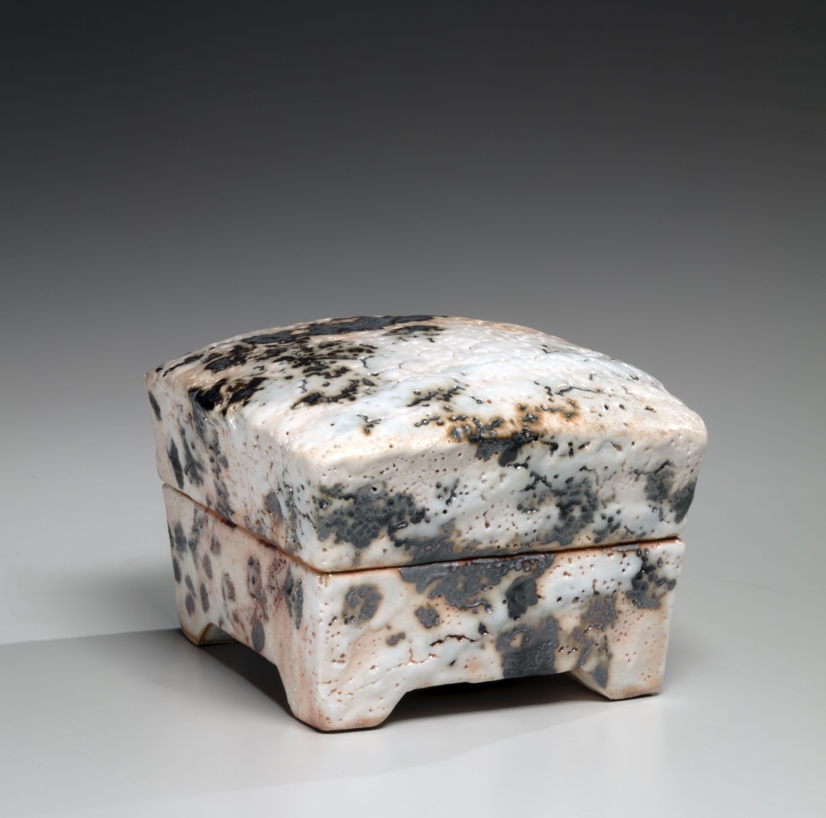 Shino-type square covered box with domed lid, cut-out foot, sloped sides and iron-oxide decoration