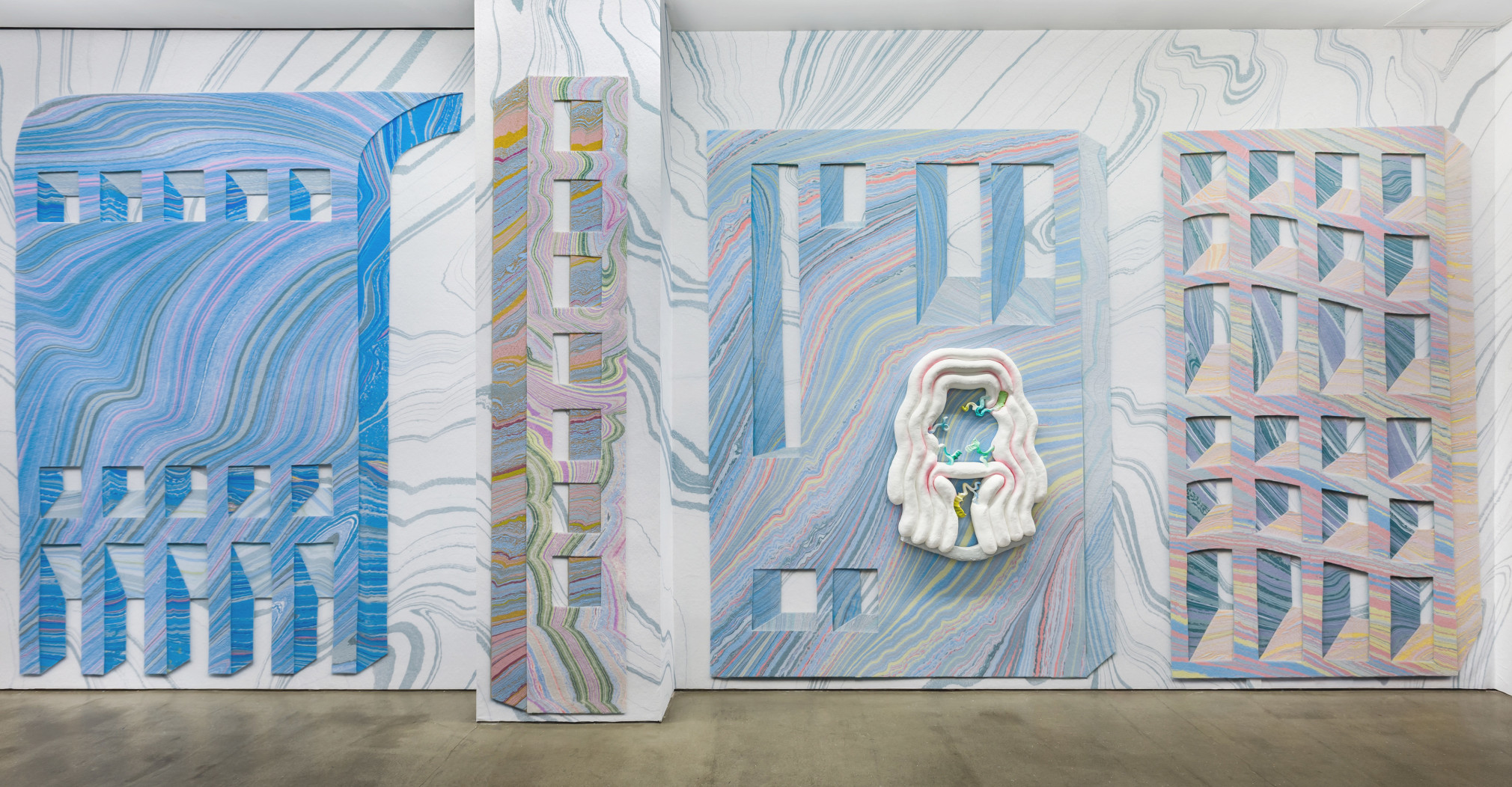 Installation view from Lauren Clay's solo exhibition. Large sculptural pieces hang on the wall. The wall is papered with custom-made wallpaper.