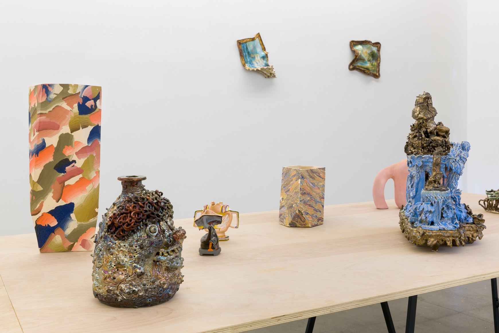 An installation view of the group exhibition &quot;Morph&quot;. There are many sculptures on a table in the gallery