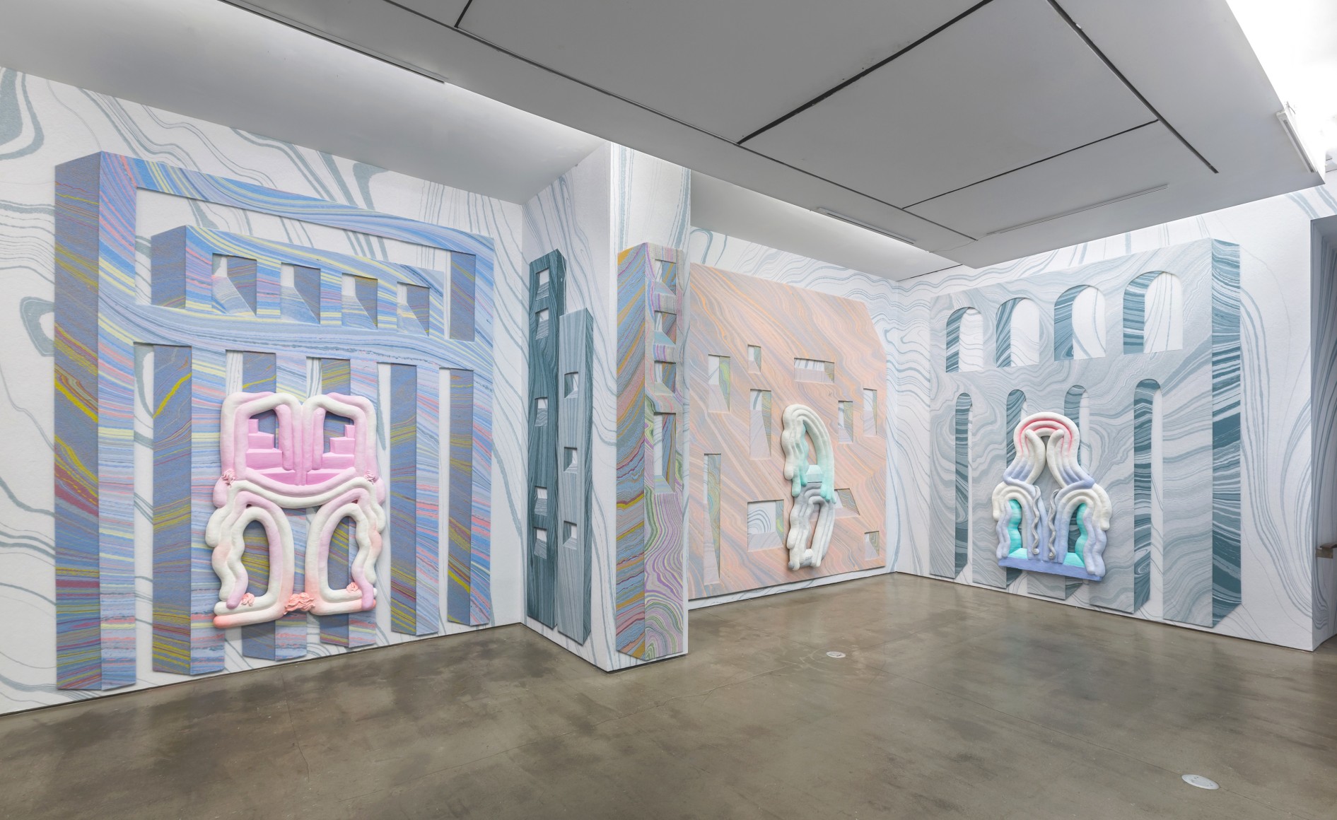 Installation view from Lauren Clay's solo exhibition. Large sculptural pieces hang on the wall. The wall is papered with custom-made wallpaper.
