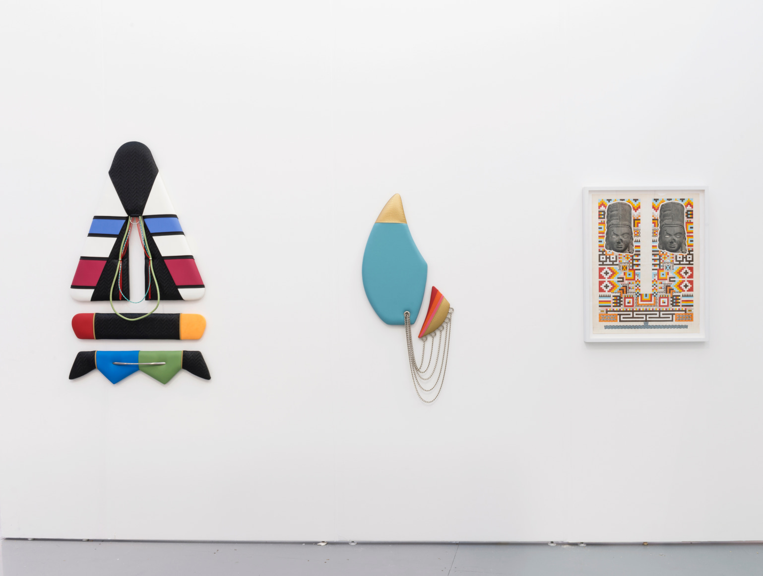 Installation view of an art fair booth. Sculptures and a collage are on the walls