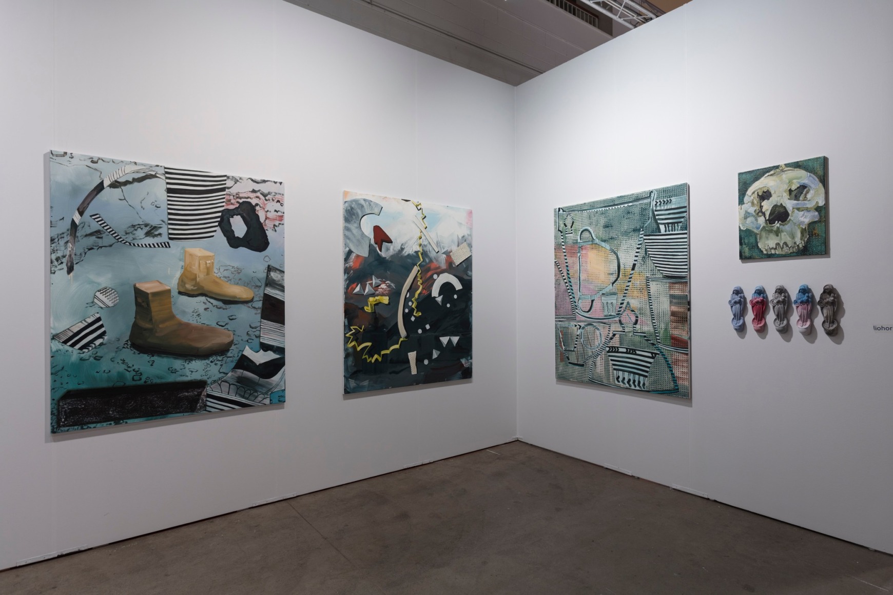 Installation view of an open art fair booth, showcasing artwork on the walls.