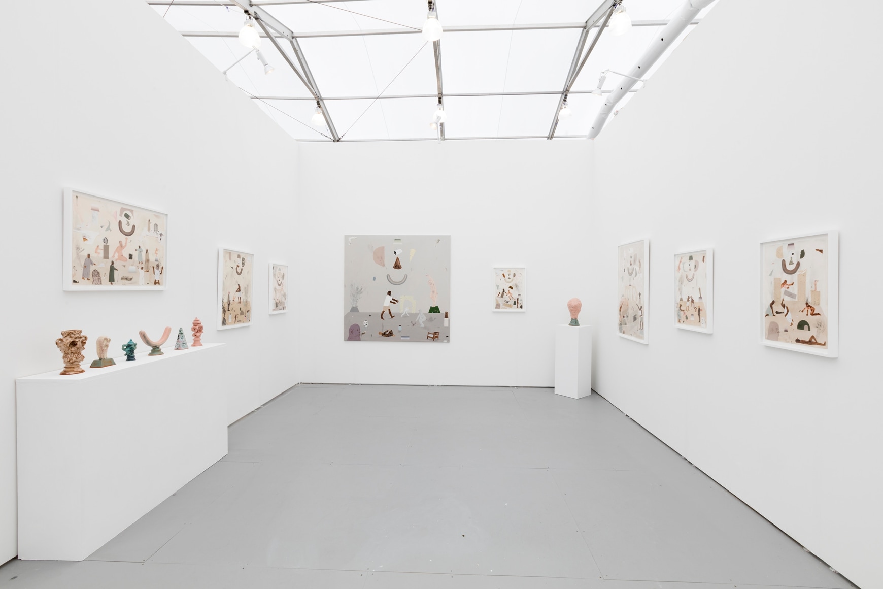 Installation image of the art fair booth at UNTITLED Miami. Framed works are on the walls and ceramic sculptures are on podiums