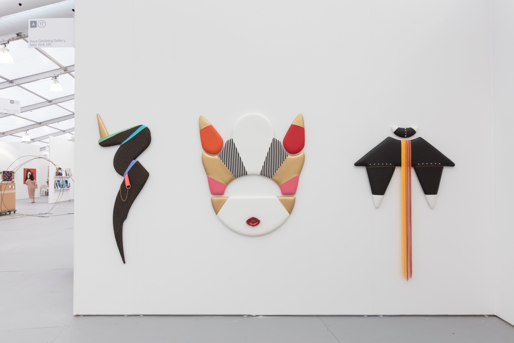 Installation view of an art fair booth, showcasing flat sculptures on the walls