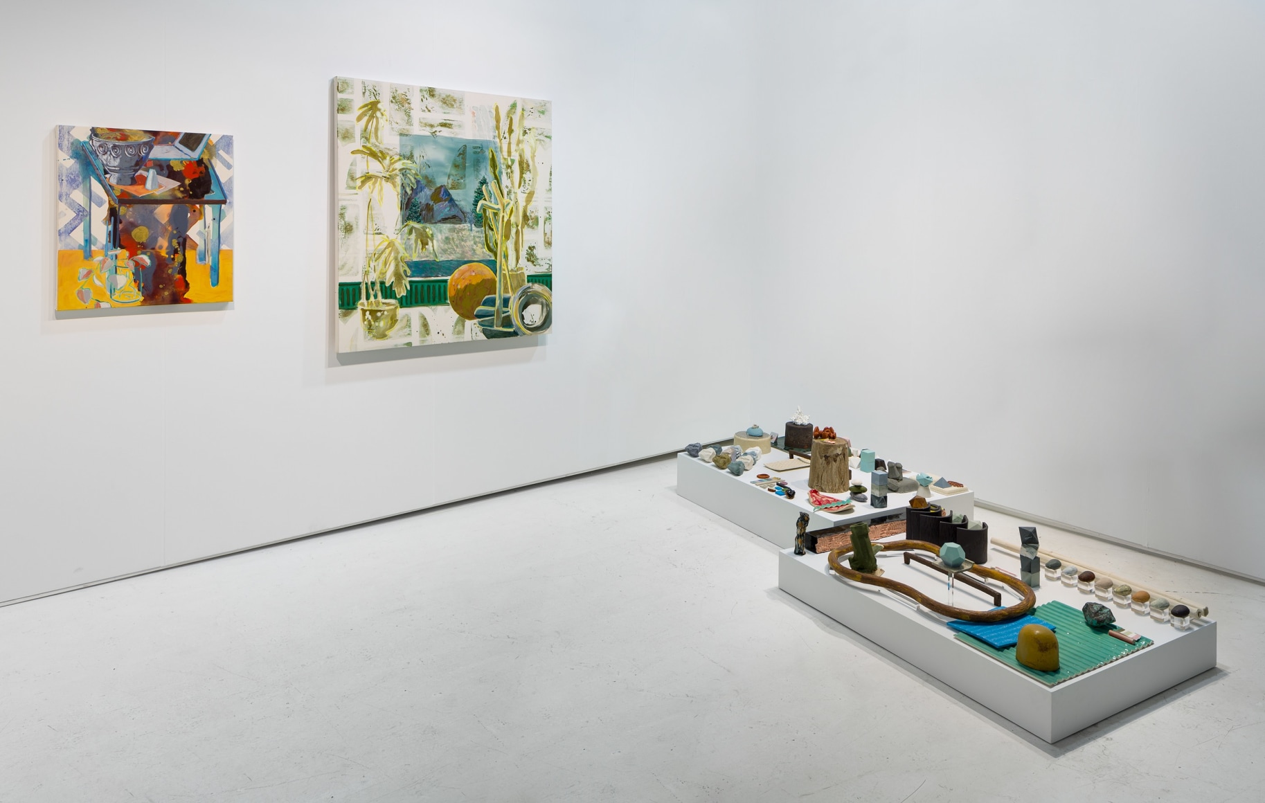 Installation of an open art fair booth, showcasing artwork on the walls. A large ceramic installation is on the floor.