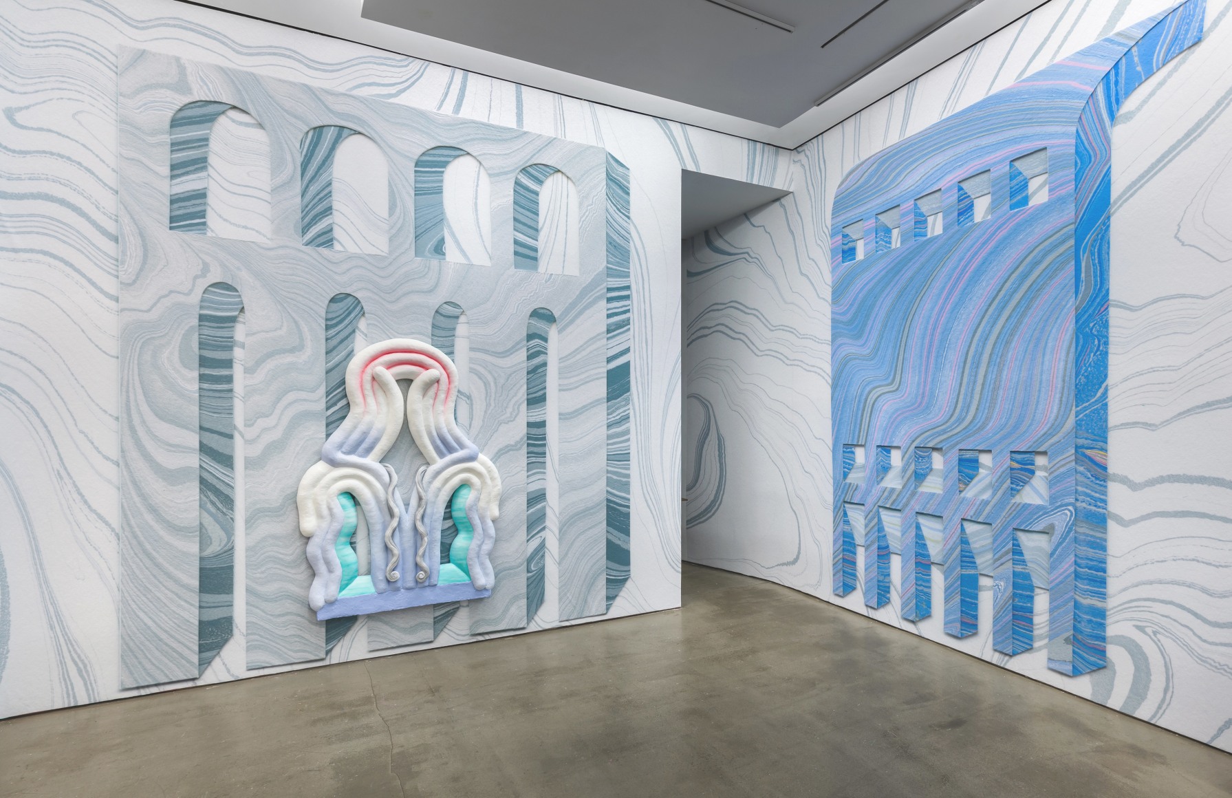 Installation view from Lauren Clay's solo exhibition. A large sculptural piece hangs on the wall. The wall is papered with custom-made wallpaper.