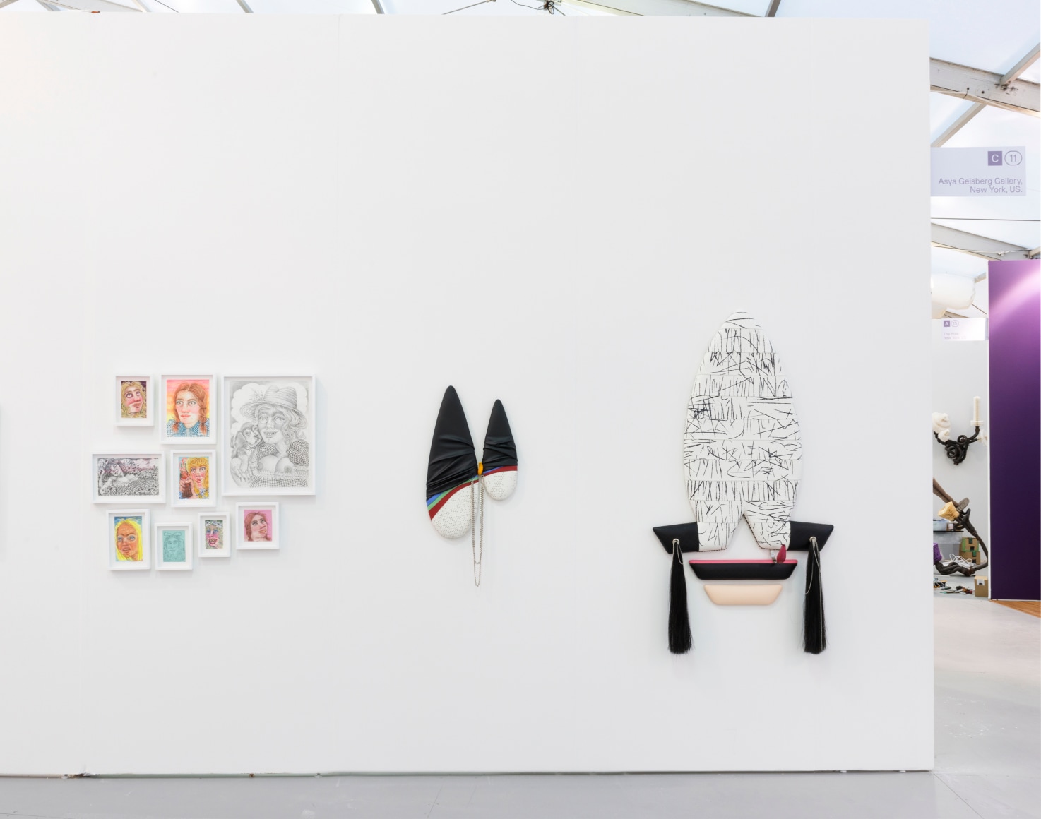 Installation view of an art fair booth. Sculptures and paintings are on the walls