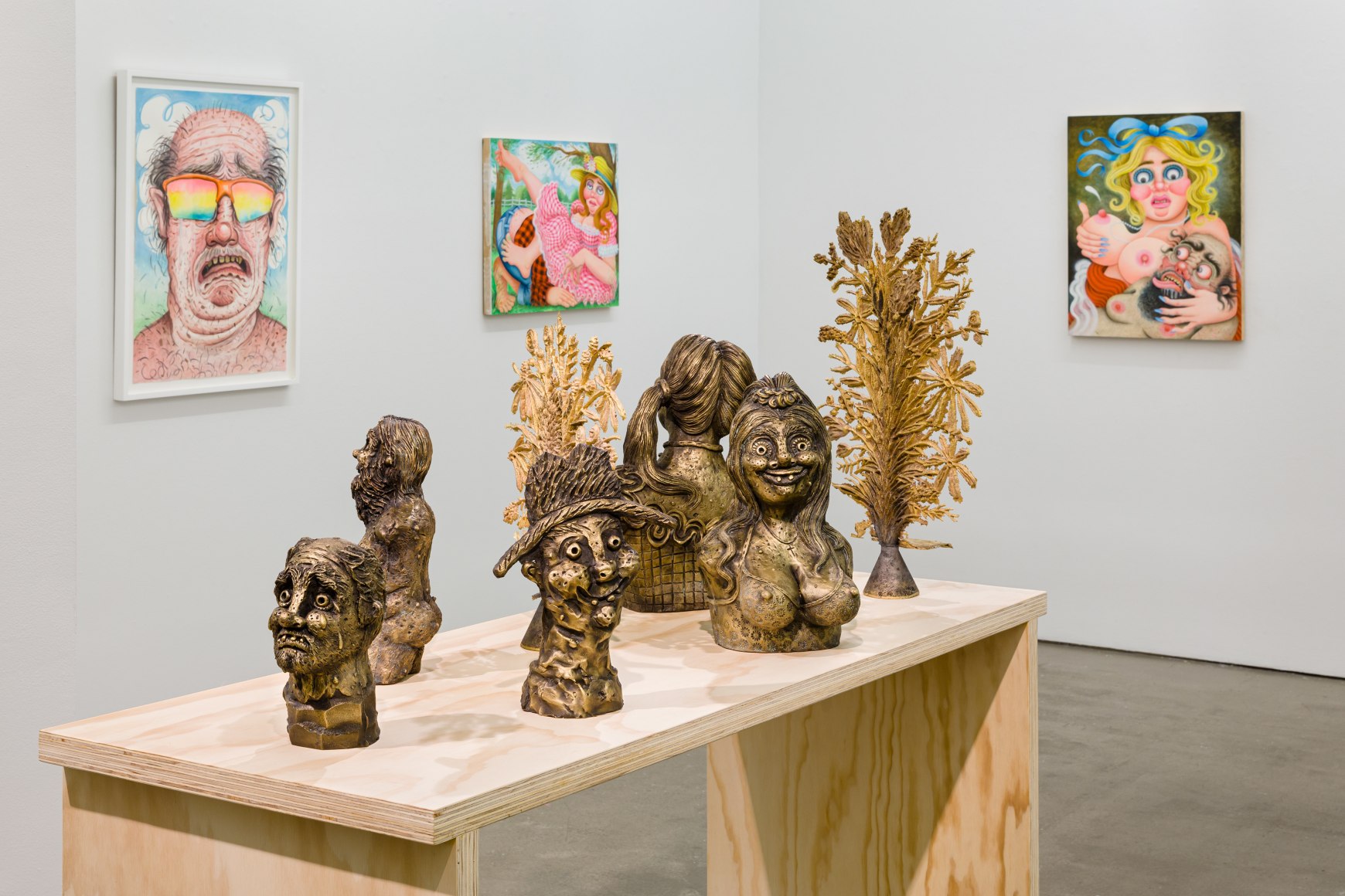 Installation view of "Town and Country" by Rebecca Morgan. Sculptures on a table and paintings and prints on the wall