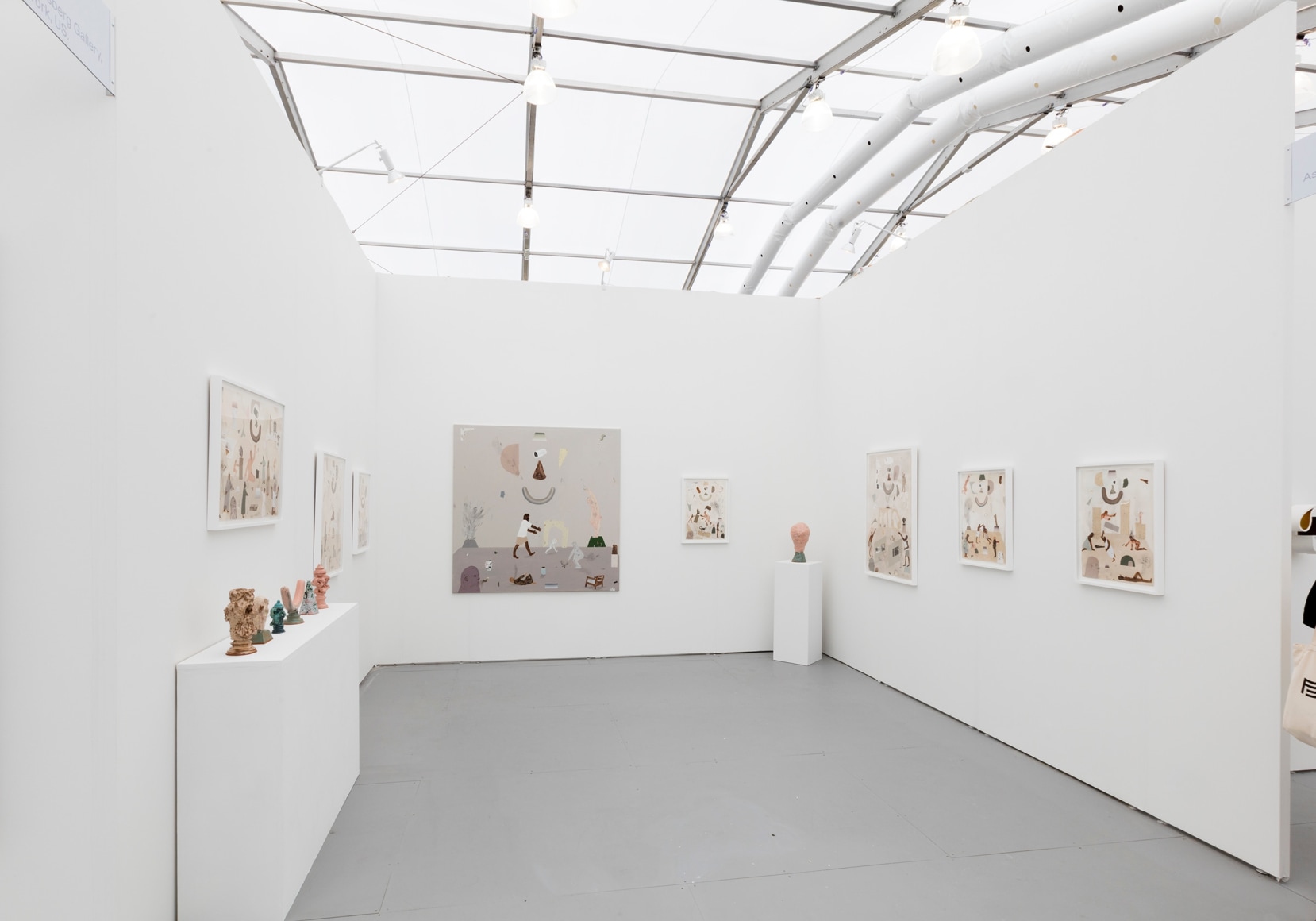 Installation image of the art fair booth at UNTITLED Miami. Framed works are on the walls and ceramic sculptures are on podiums