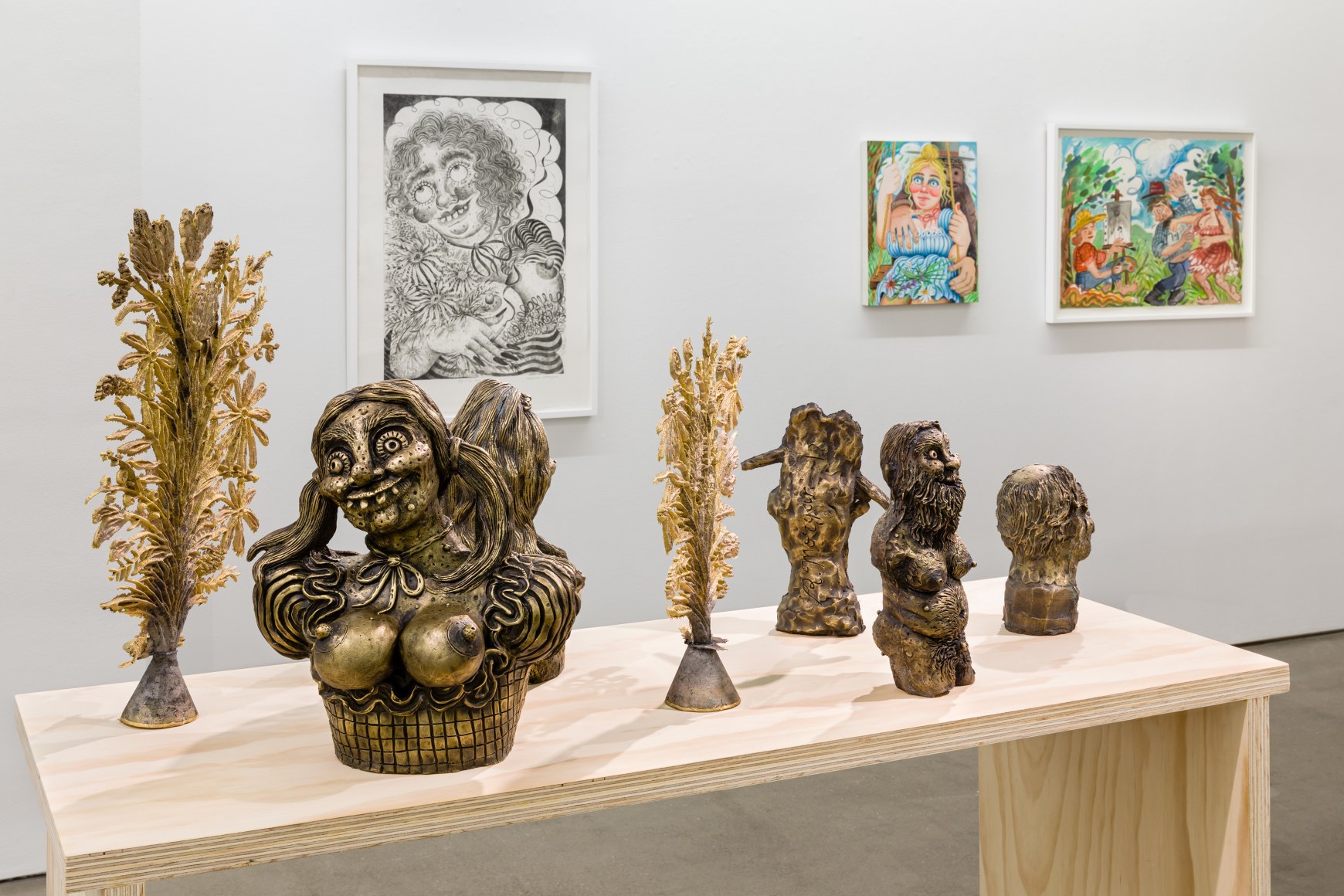 Installation view of "Town and Country" by Rebecca Morgan. Sculptures on a table and paintings and prints on the wall