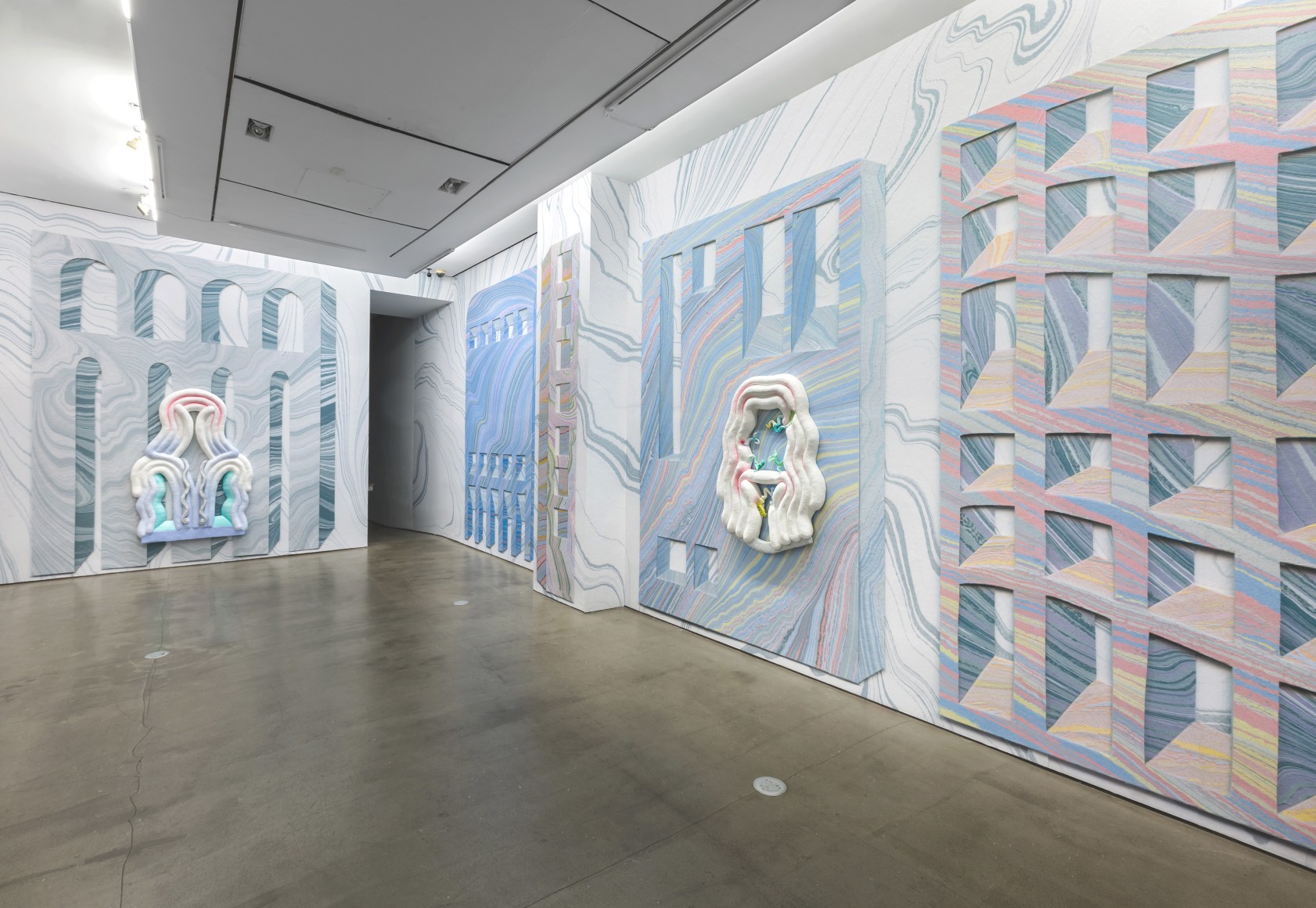 Installation view from Lauren Clay's solo exhibition. Large sculptural pieces hang on the wall. The wall is papered with custom-made wallpaper.