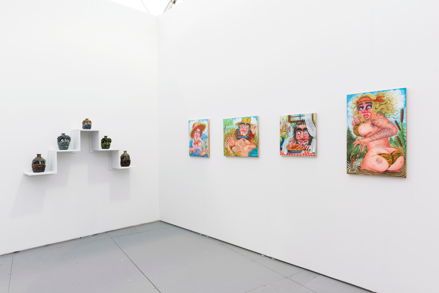 Installation view of an art fair booth. Sculptures and paintings are on the walls