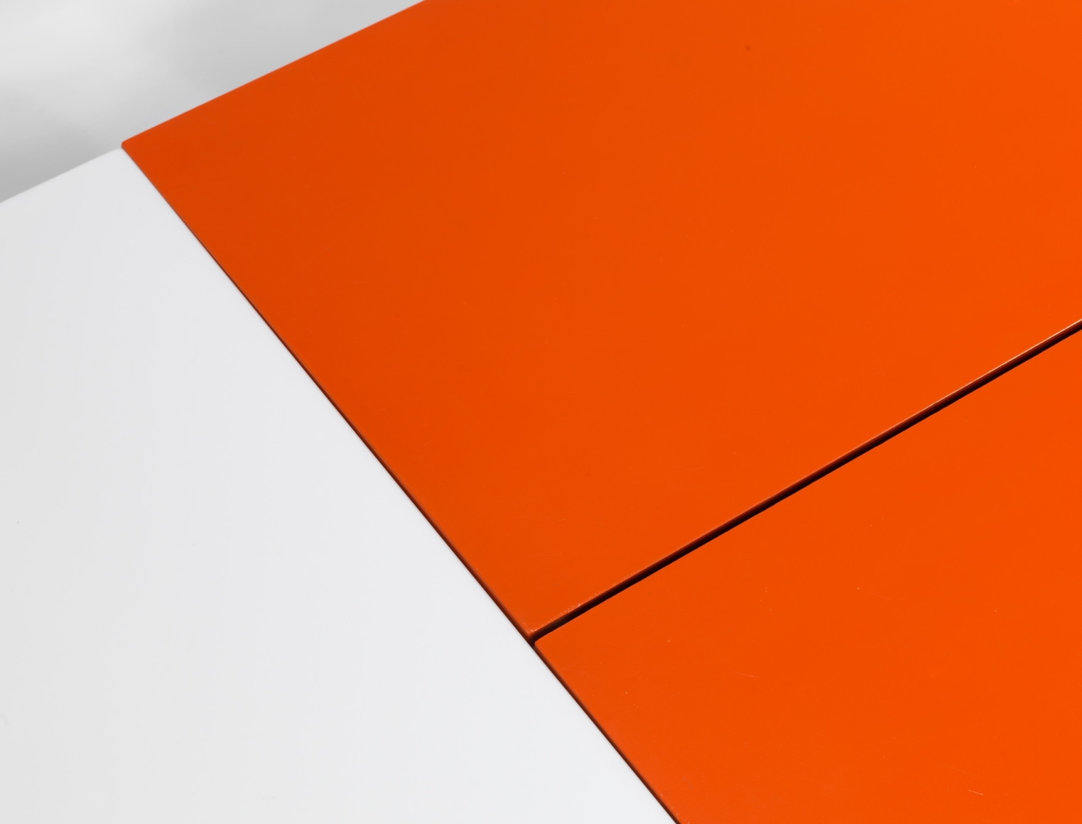 photograph of low table by Motte in a blank room, top of table is half orange and half white