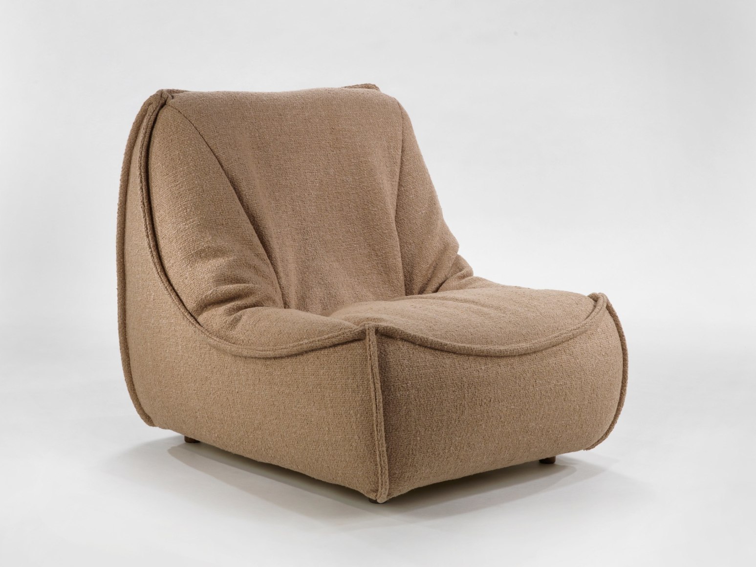 photograph of chair by Govin in a blank room, chair is brown and sits low to the floor