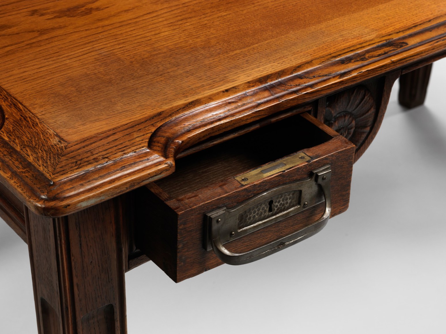 photograph in blank room of desk by Gauthier made in wood with detailing throughout, four legs and drawers.
