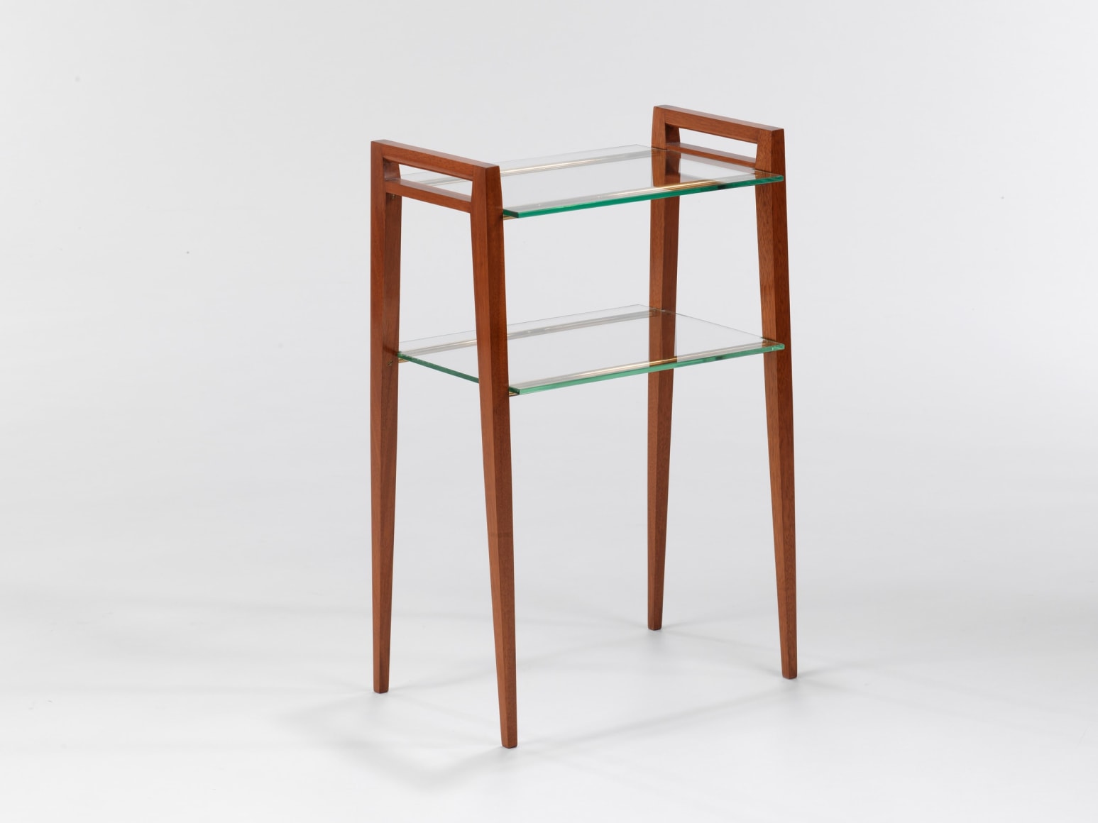 Two tier glass table with wooden legs in front of white background