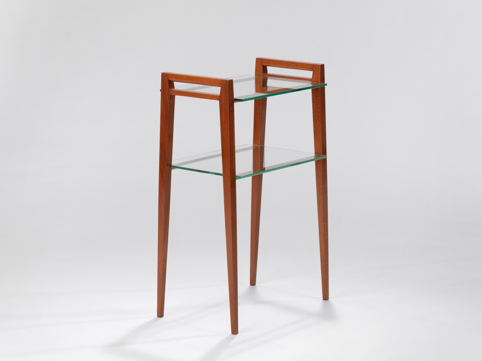 Two tier glass table with wooden legs in front of white background