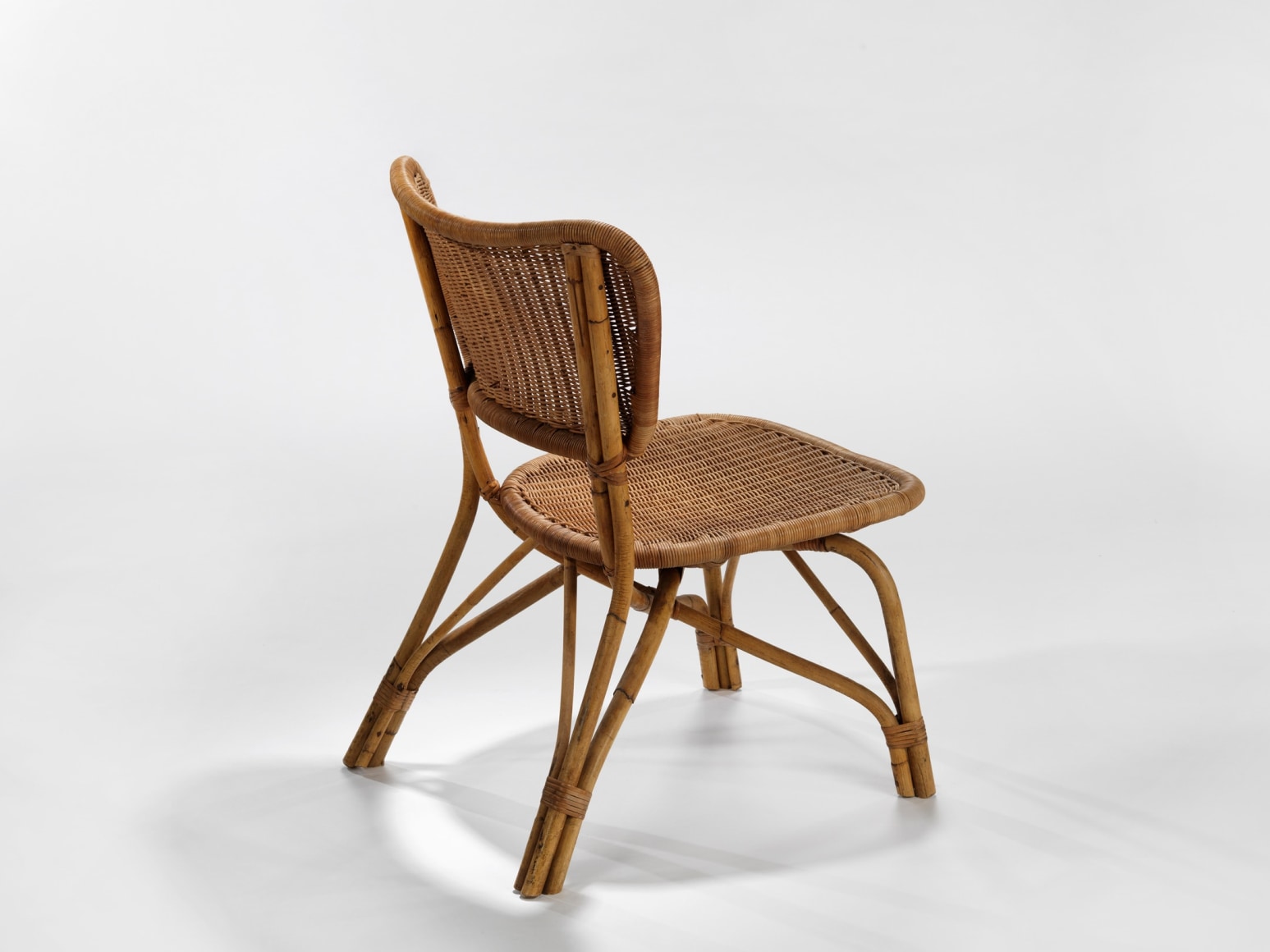 photograph of a rattan chair in a blank room