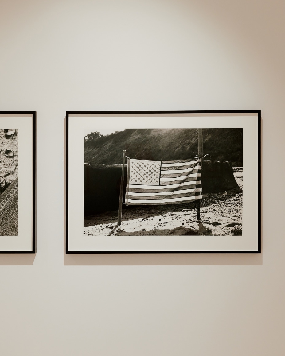 black and white photograph of an American flag on the beach