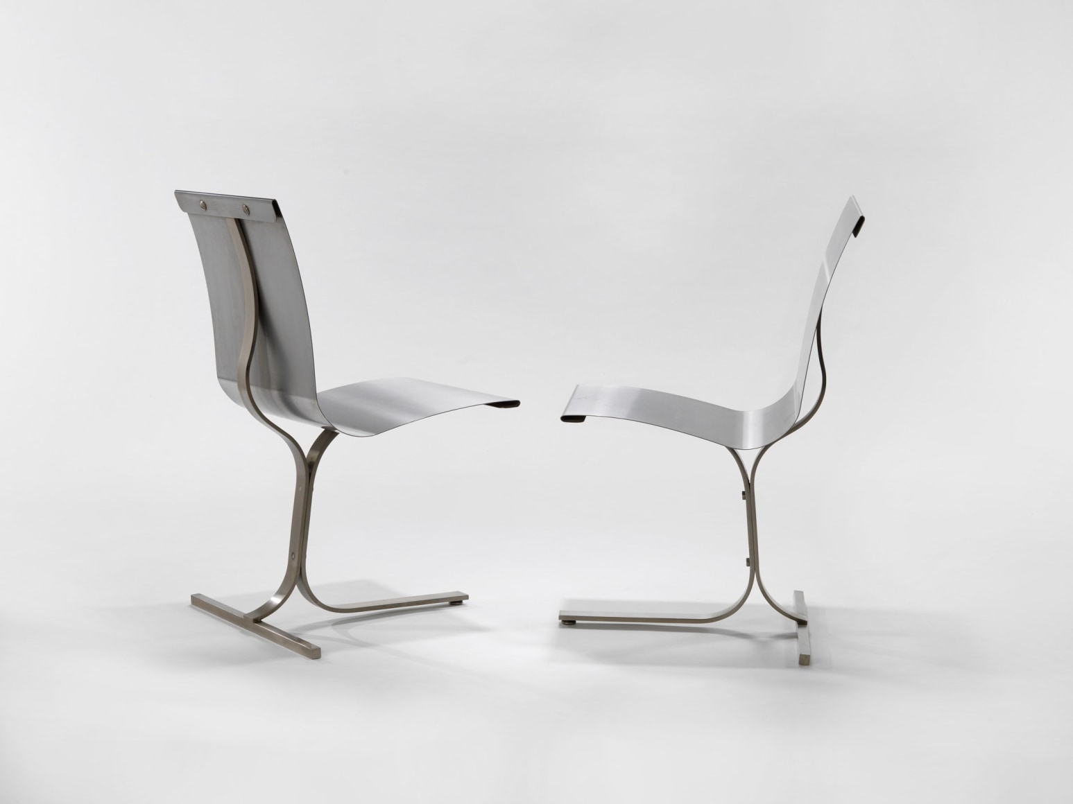 photograph of 2 steel chairs in a blank room