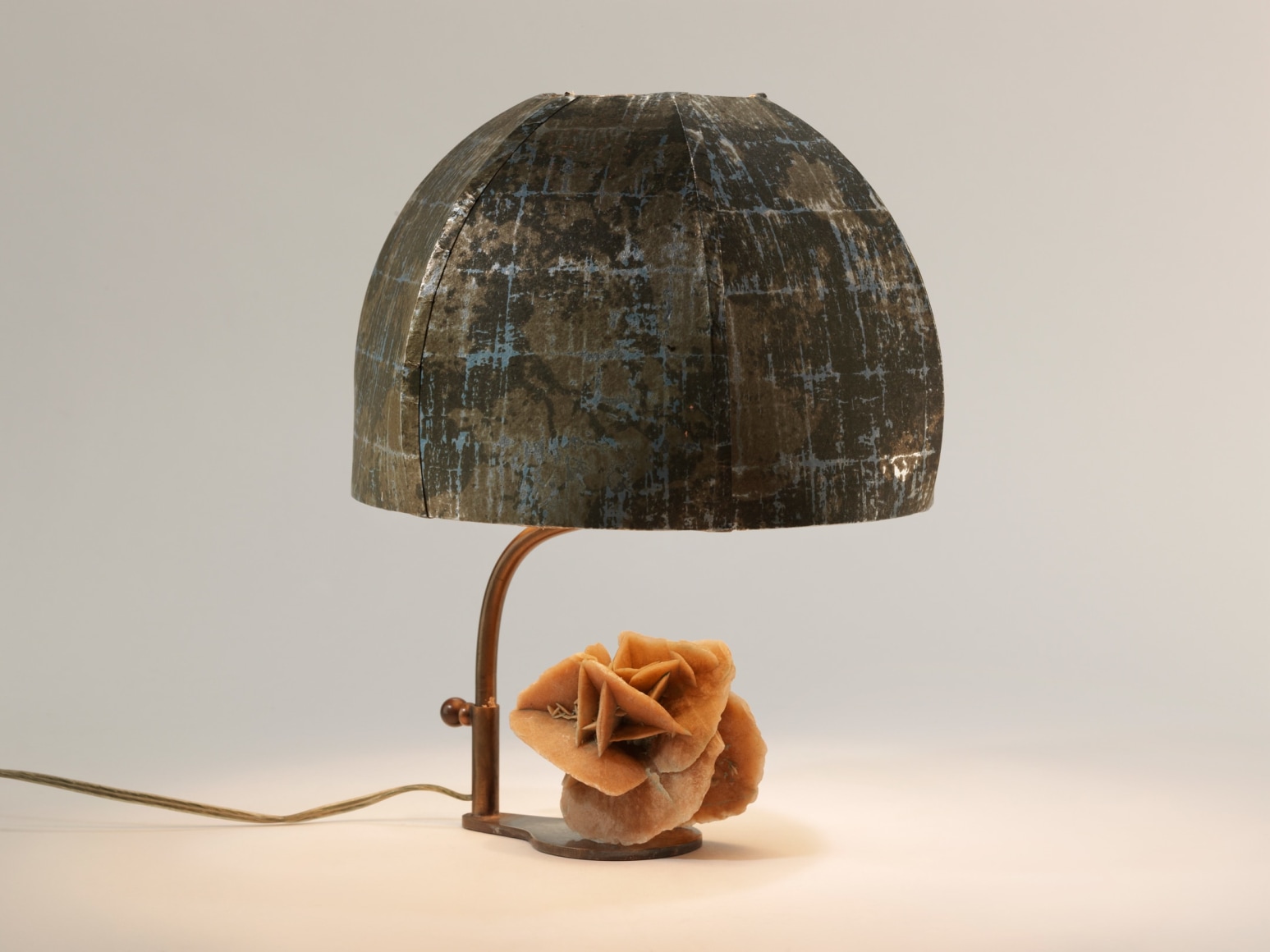 photograph of a lamp with a round shade and a sculpture of a rose at its base