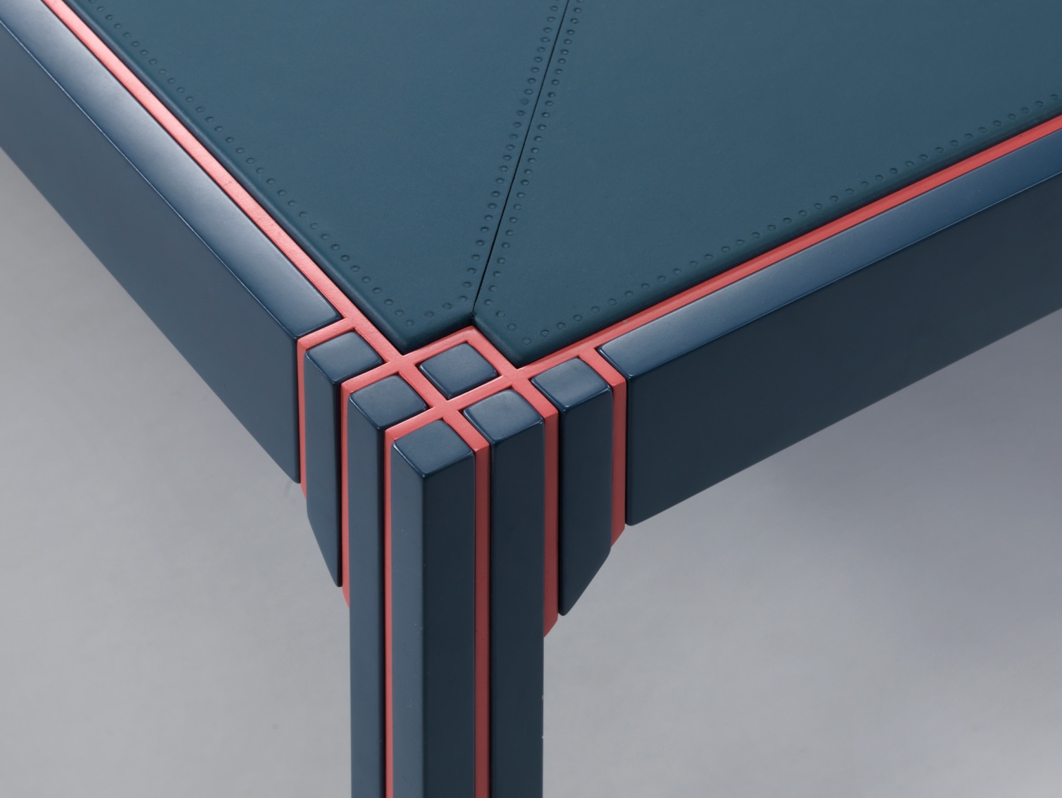 Close up of corner of blue lacquered table and orange painted detailing