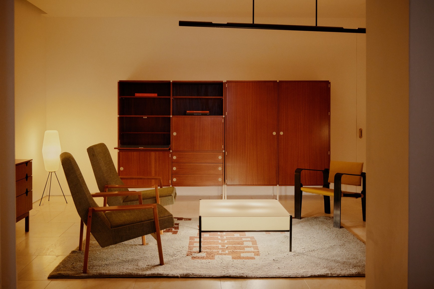 Upholstered and wooden armchairs, illuminated coffee table with black metal legs, wooden secretary cabinet, and wooden armoire by Pierre Guariche/ A.R.P. with