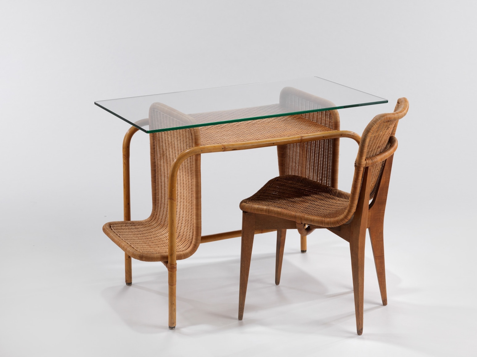 rattan desk with glass top, pictured with a rattan chair by Louis sognot