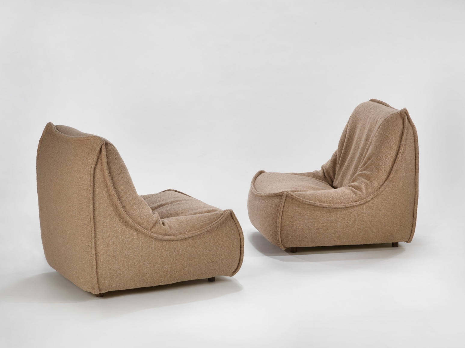 photograph of 2 chairs by Govin in a blank room, chair is brown and sits low to the floor