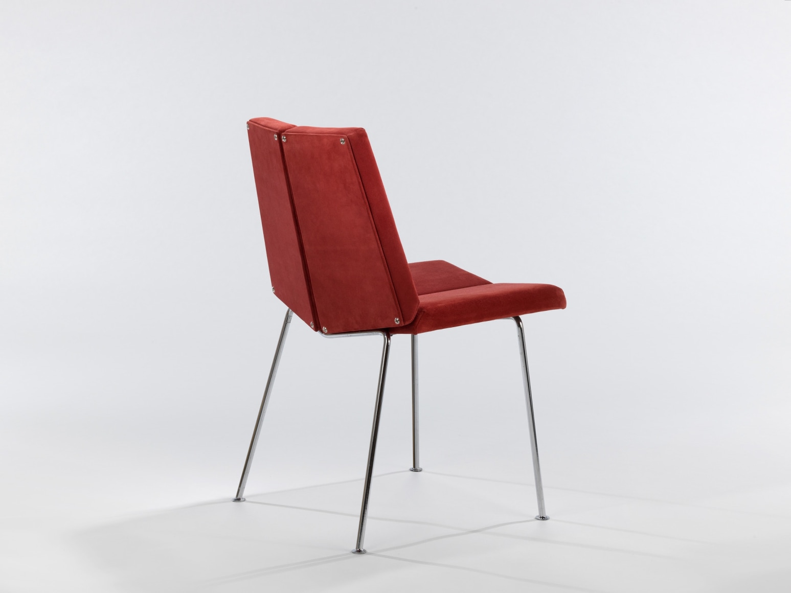 Single chair in red suede made by Pierre Guariche facing backward.