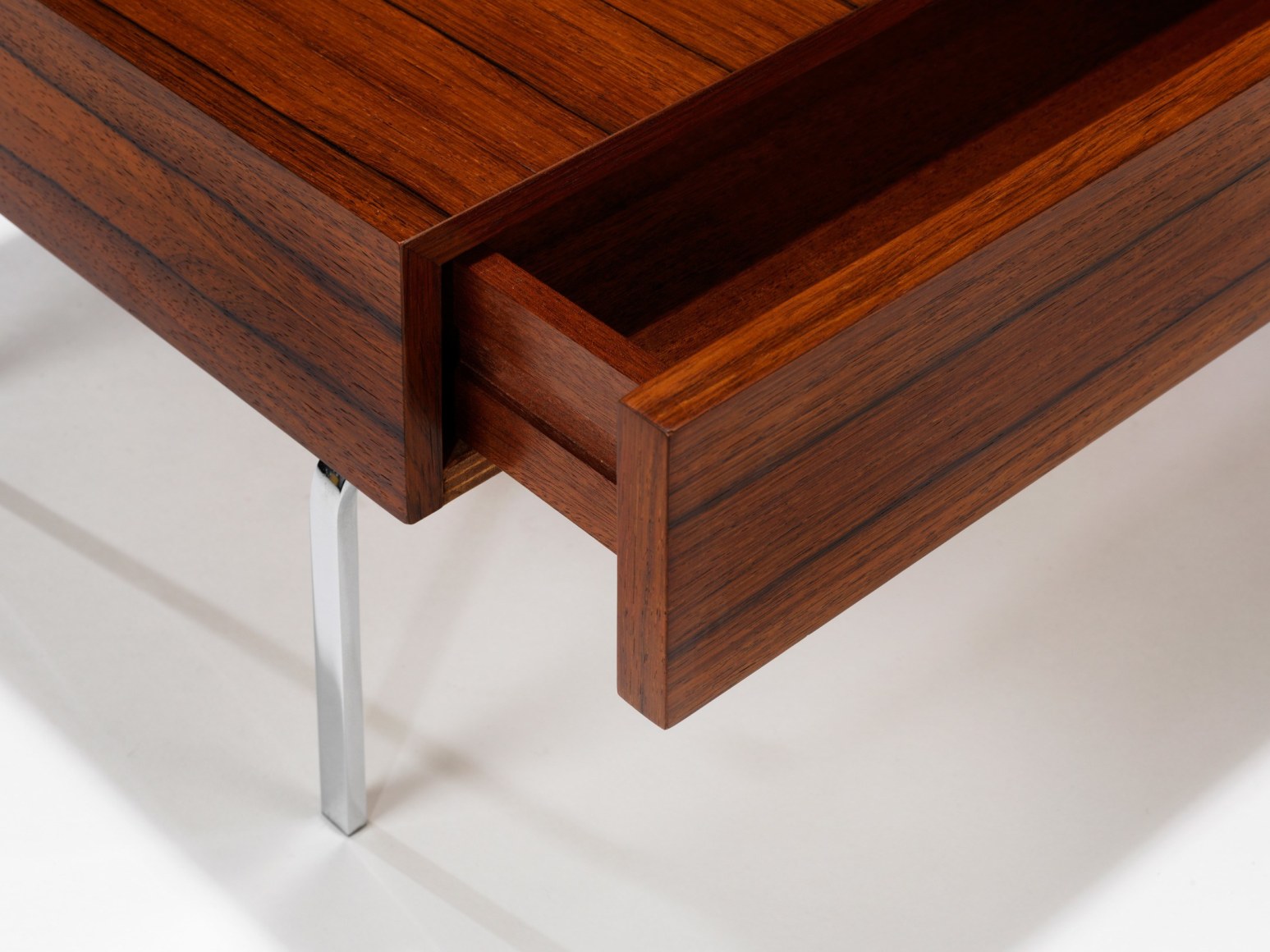 up close photograph of side table by Fermigier, tables have metal legs and teak tops