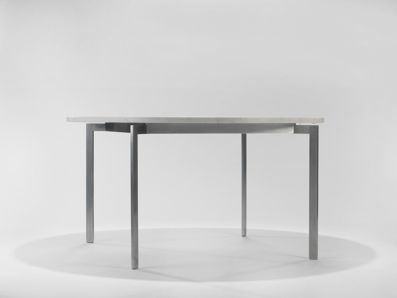 photograph of a table with steel legs and a marble top in a blank room