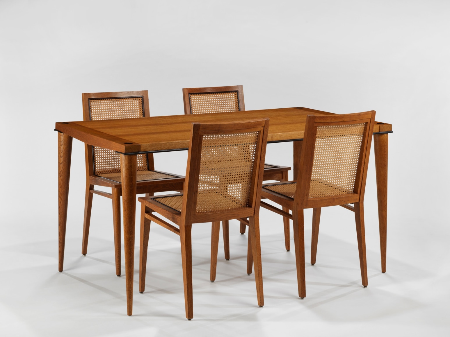 photograph of 4 wood chairs around a wood dining table in a blank room