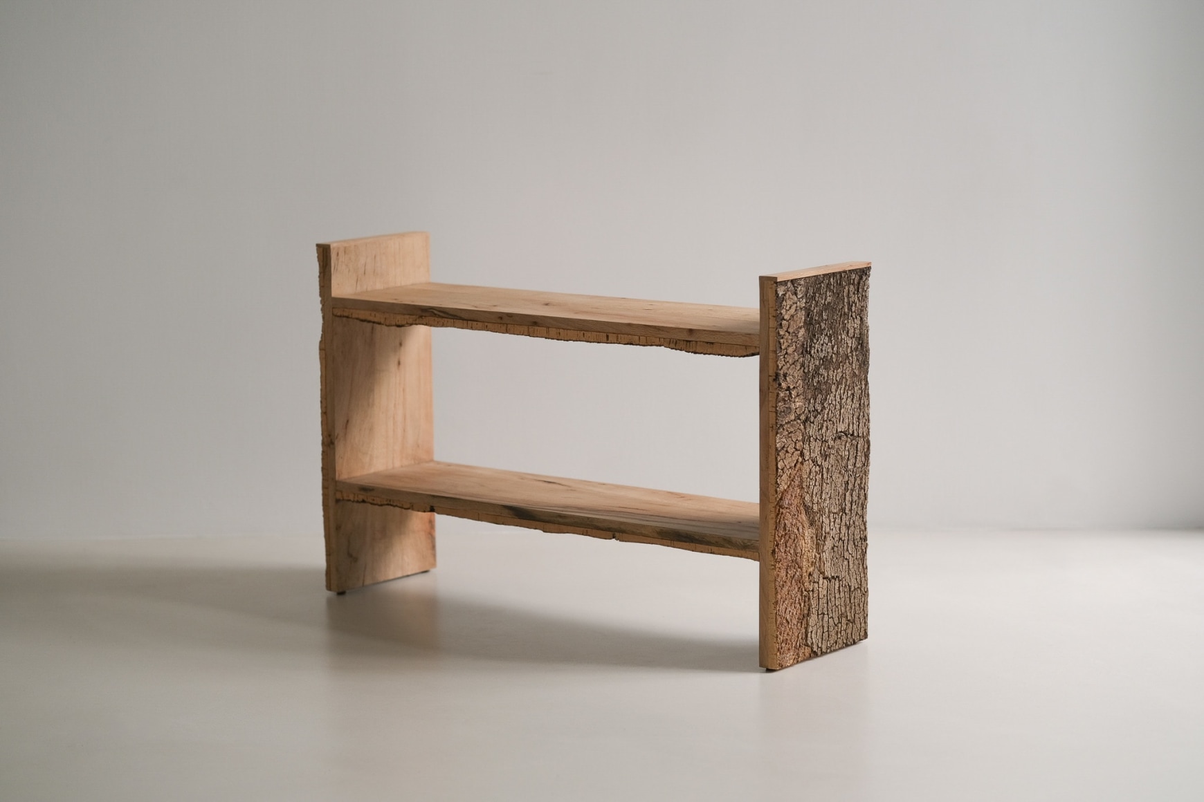 Bookshelf made of oak and cork standing against a grey background.