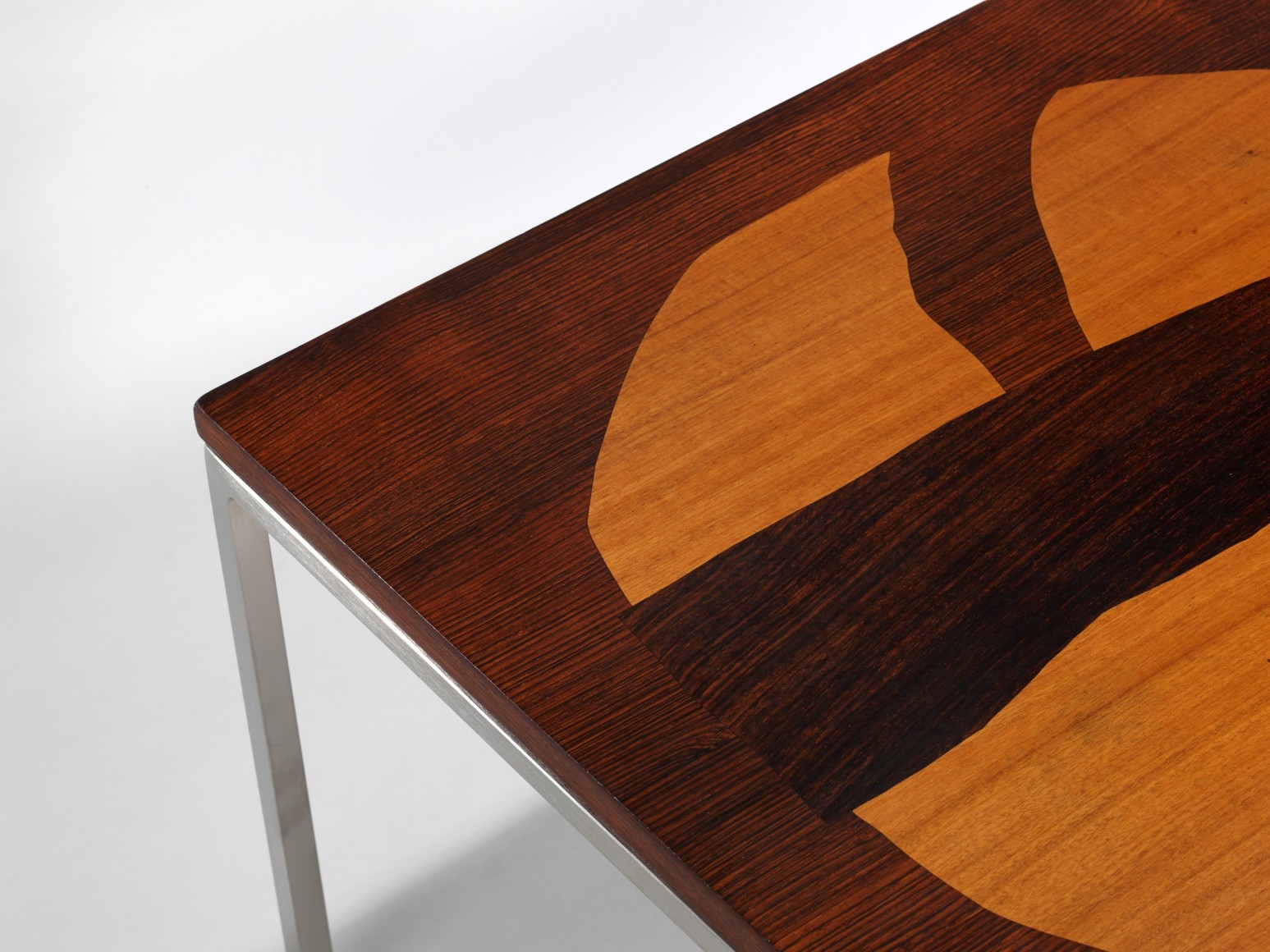 Wooden coffee table with marquetry and chrome metal legs in front of white background