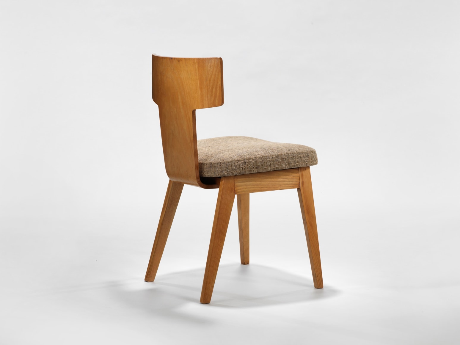 photograph of a chair with beige apholstery in a blank room