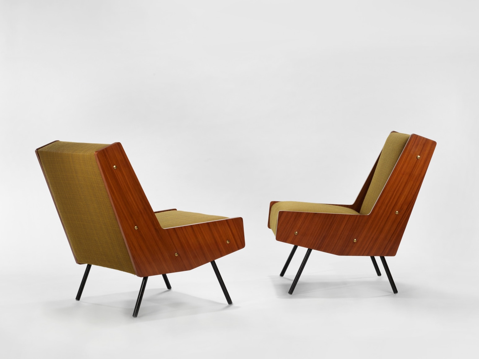 photograph of chair by Motte in a blank room, chair is made of painted metal, mahogany, and fabric