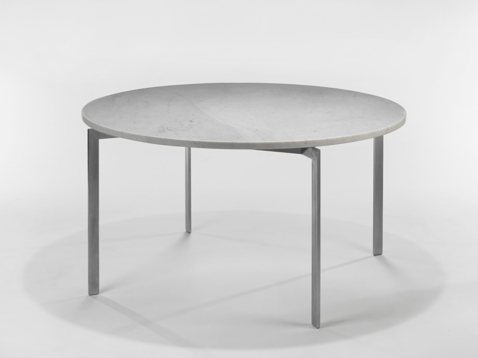 photograph of a table with steel legs and a marble top in a blank room