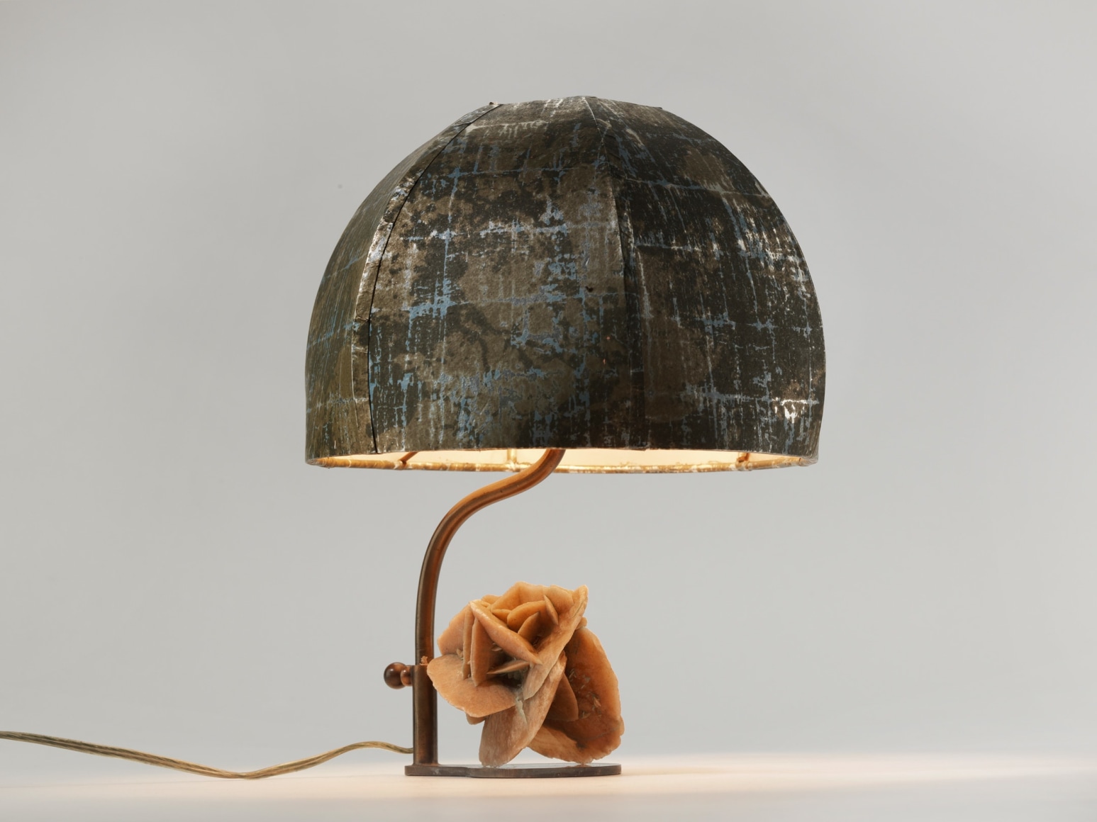 photograph of a lamp with a round shade and a sculpture of a rose at its base