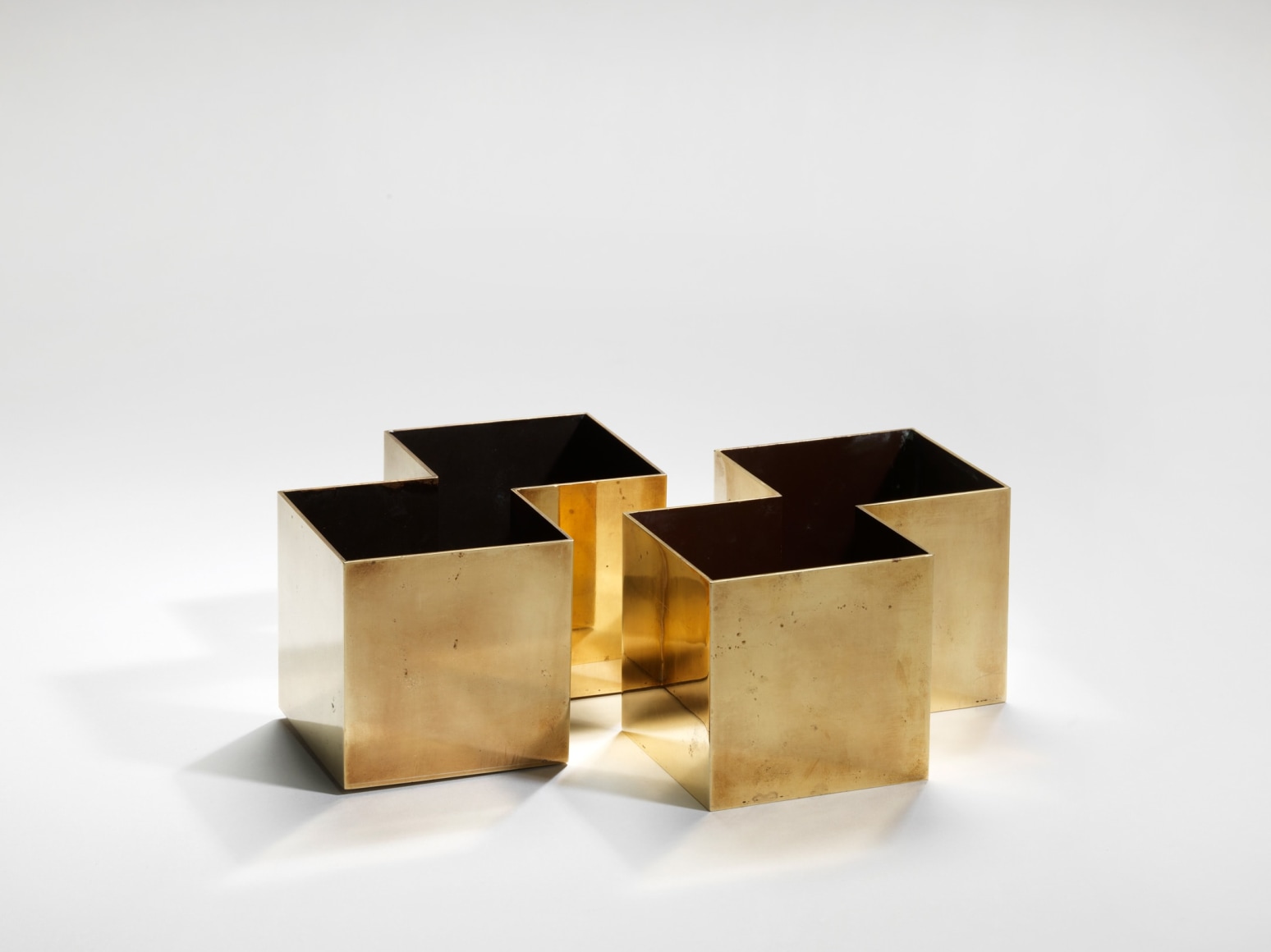 photograph of four gold square vases with black interiors in a blank room