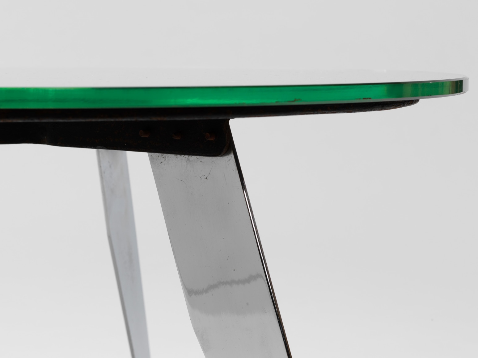 photograph of table in a blank room with metal legs and a glass top